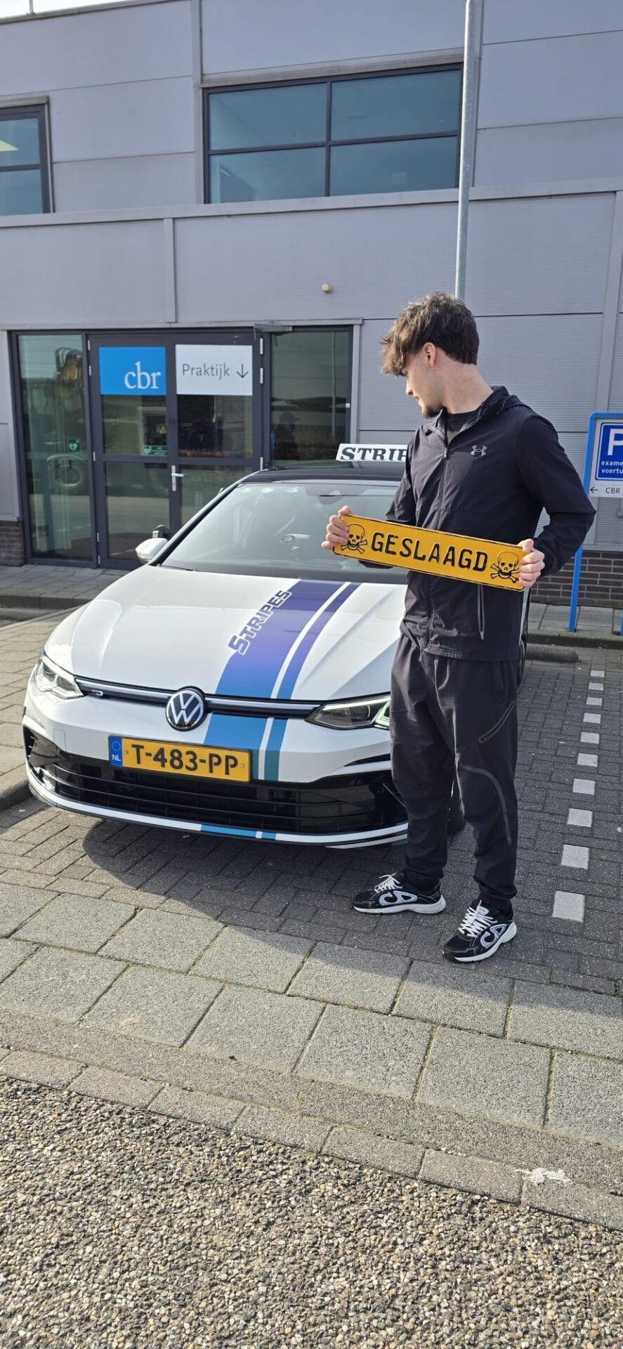 Geslaagde leerling met geslaagd-bord bij de schakel lesauto van Rijschool Stripes