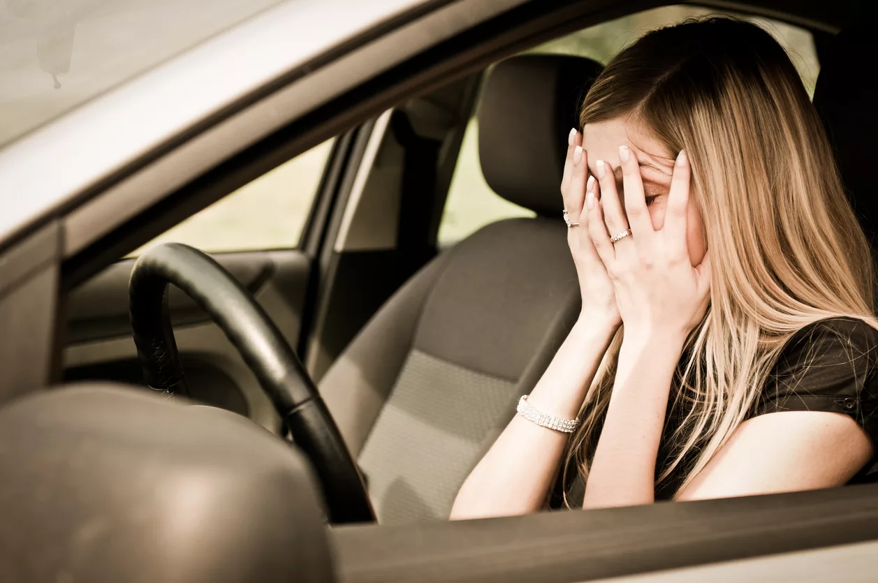 Een persoon die op de bestuurdersstoel van een auto zit en schijnbaar gestresst of angstig is, wat de faalangst rijlessen illustreert.